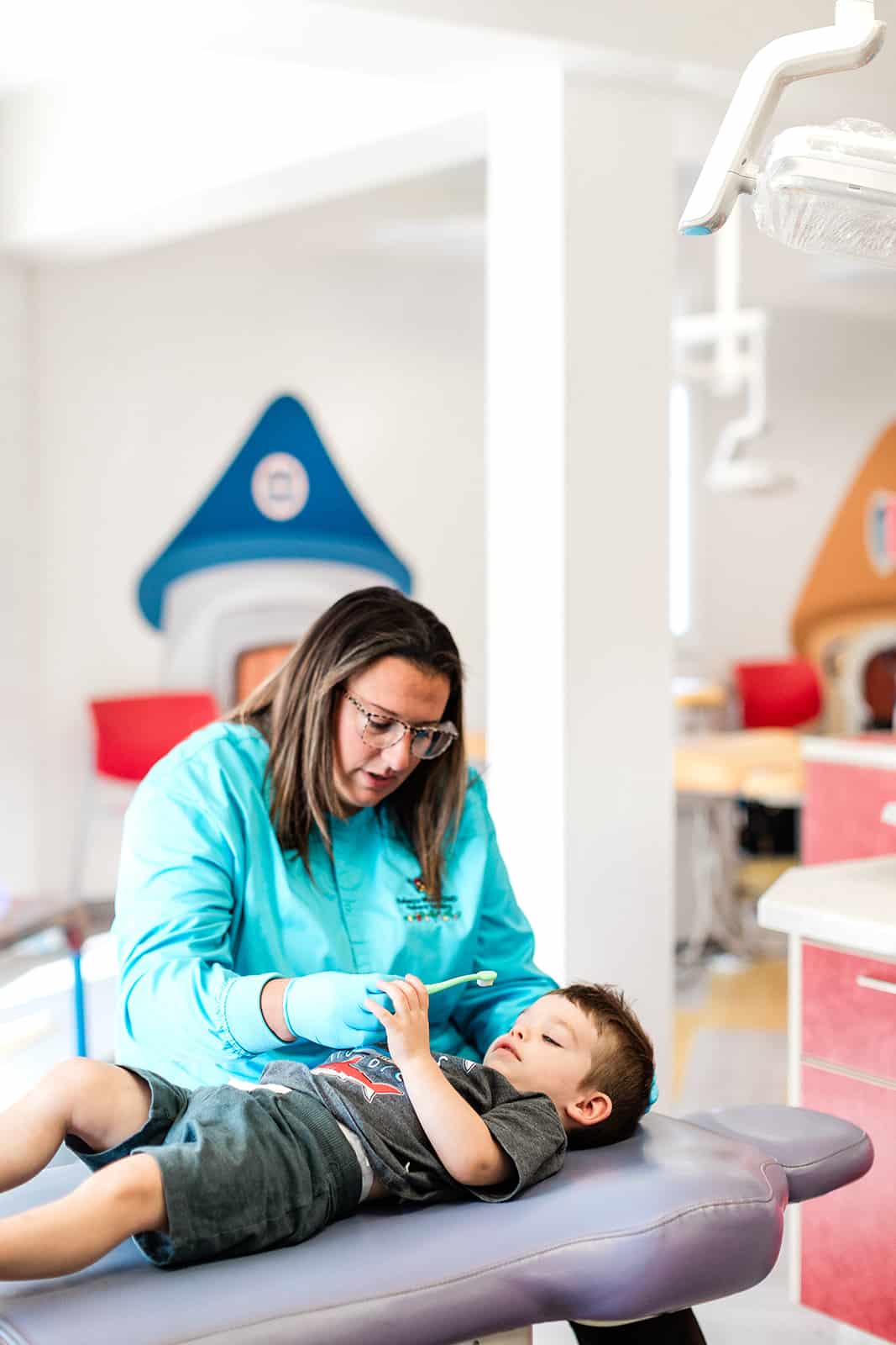 A staff member showing a pediatric dentistry patient a toothbrush